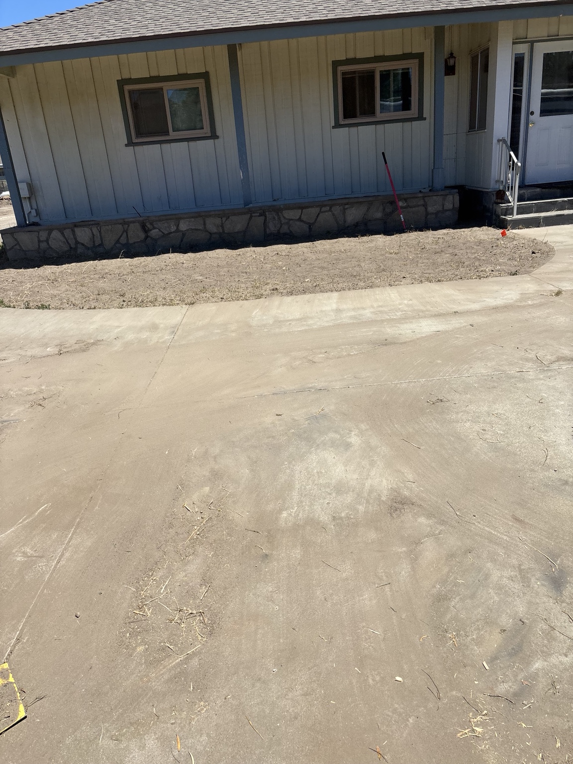 Cleared planting border beside a home and concrete path